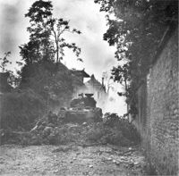 Infantry take cover behind Sherman tank during street fighting. 